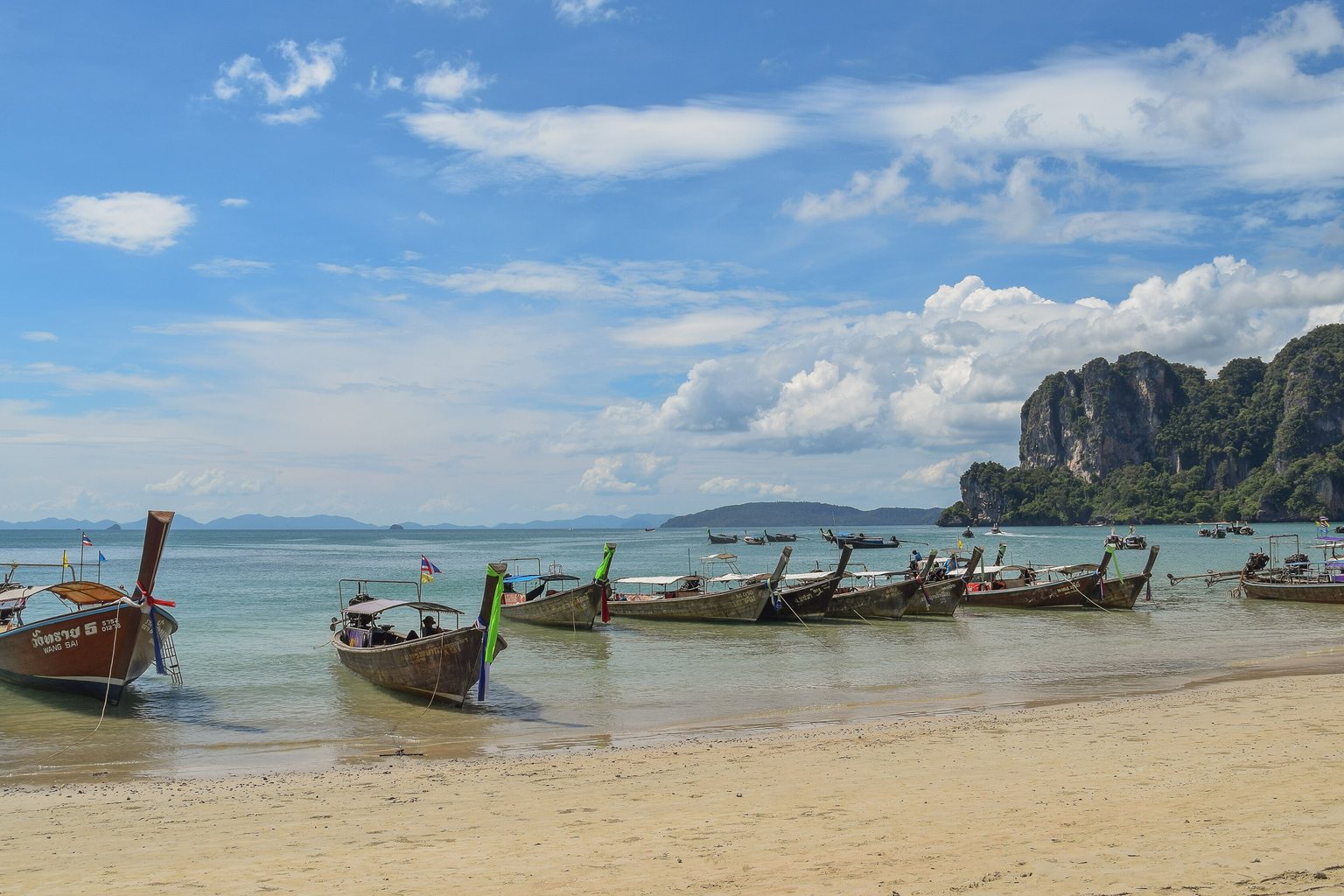 Bateaux à longue queue sur la plage de Railay Ouest, près de Krabi, au pied des falaises calcaires